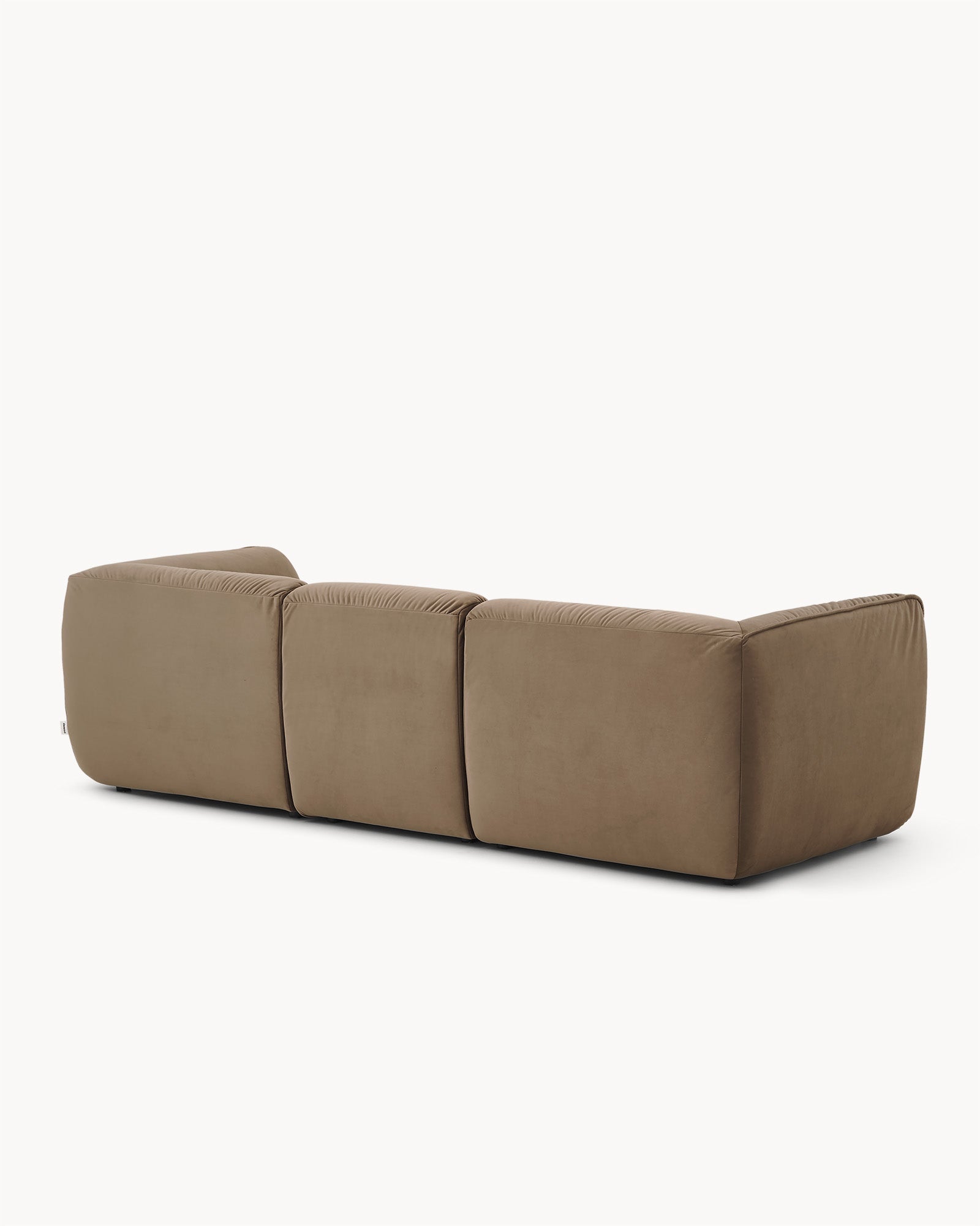Sofa trzyosobowa CALM - sofa trzyosobowa widoczna z boku, z zaokrąglonymi krawędziami i prostymi liniami. Zbliżenie na tylną część mebla z wyraźnymi przeszyciami.