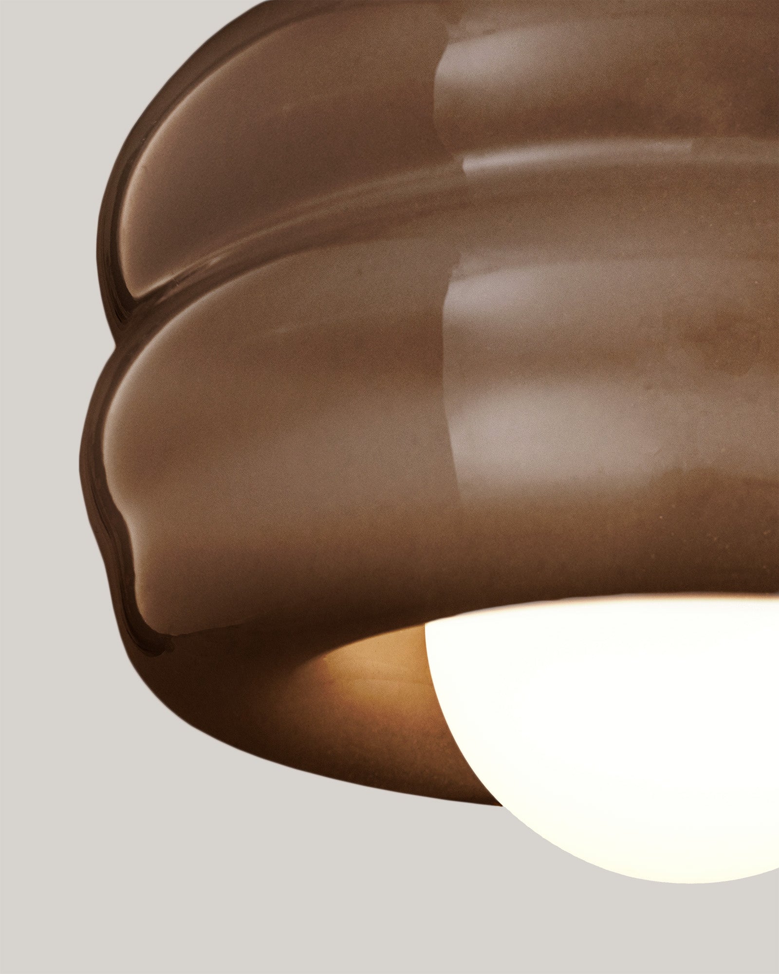 Lampa BUNS - zbliżenie na lampę z okrągłym kloszem i falistym wykończeniem. Widok z boku ukazuje detale konstrukcji.